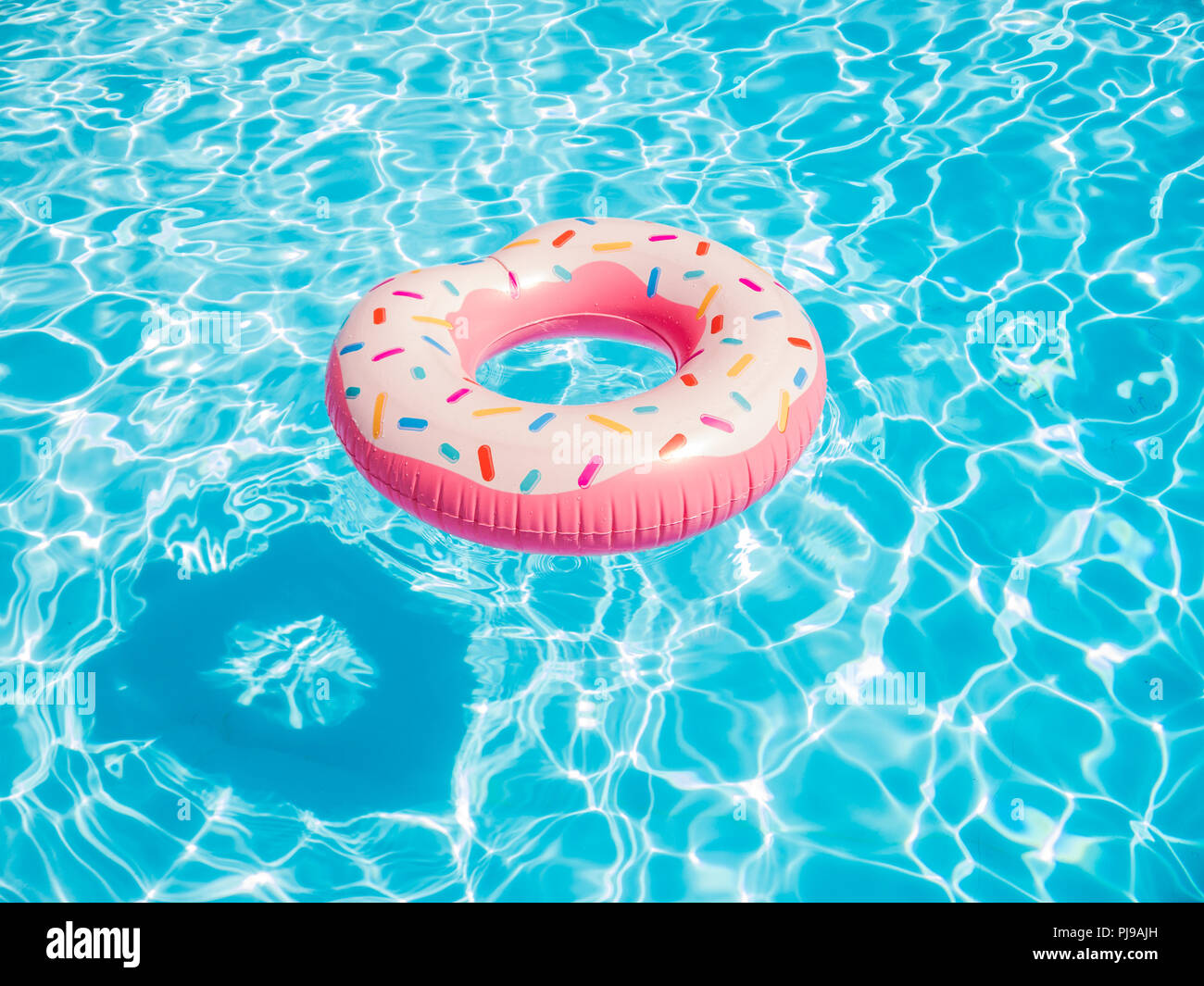 Rosa Aufblasbare Donut schwimmen Ring in einem Pool Stockfoto