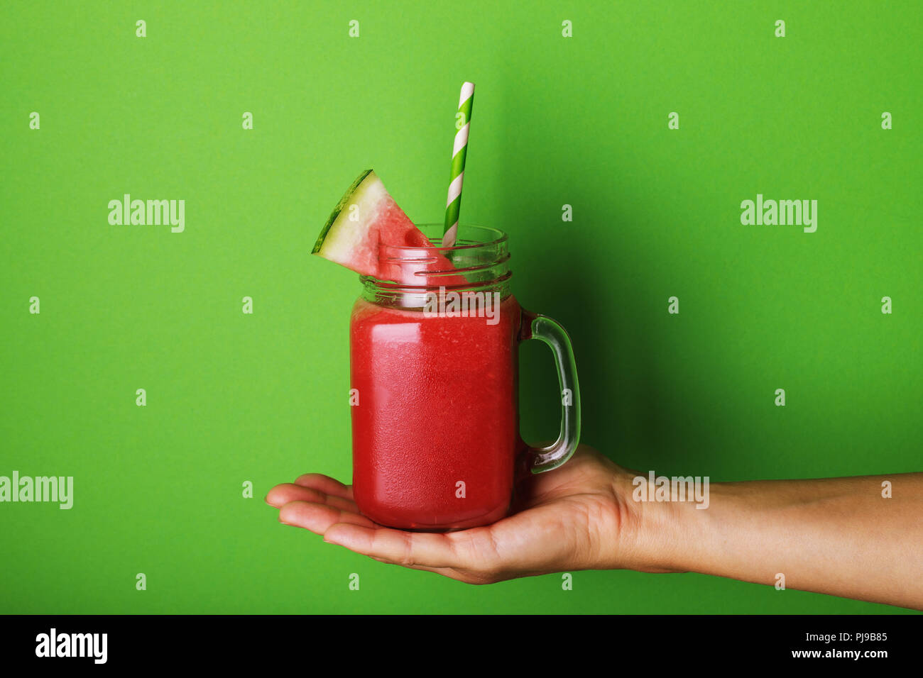 Smoothies aus eine Wassermelone in transparenten jar auf grünem Hintergrund in die Hände des Menschen gekocht Stockfoto