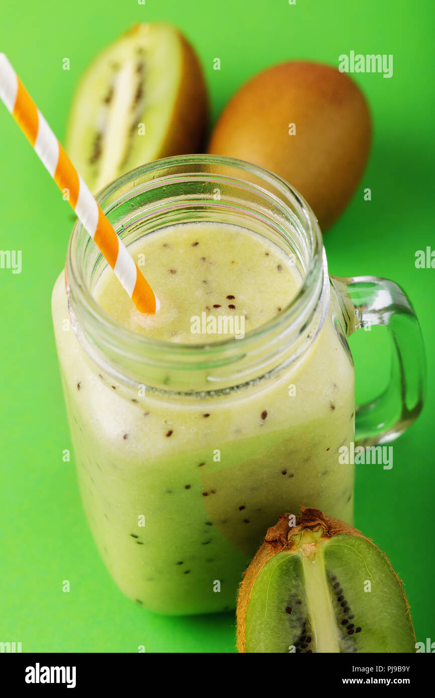 Smoothies aus reifen Kiwi in einem durchsichtigen Glas gekocht mit Obst auf einem grünen Tisch Stockfoto