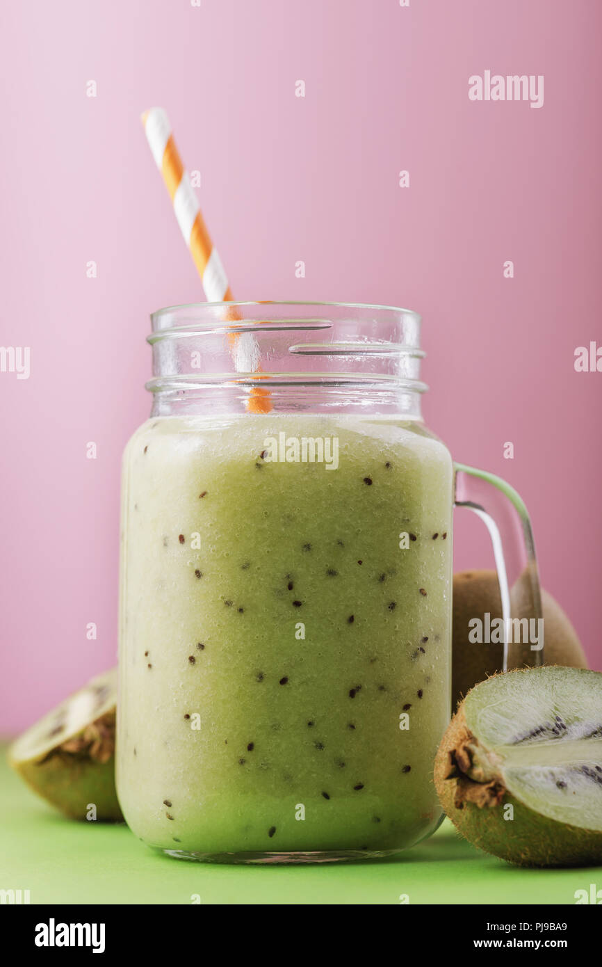 Smoothies aus reifen Kiwi in einem durchsichtigen Glas gekocht mit Obst auf rosa Hintergrund Stockfoto