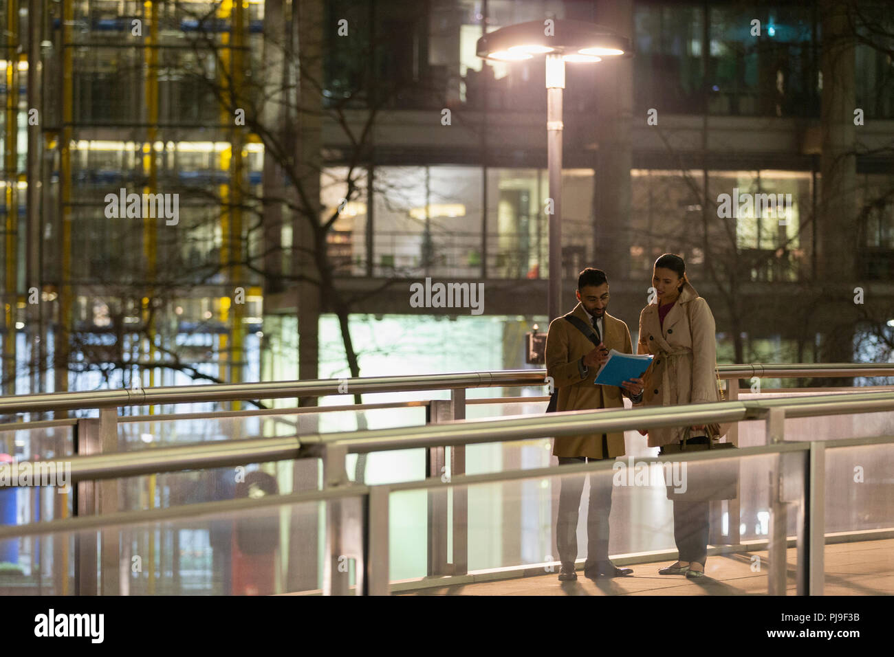 Geschäftsleute Schreibarbeit diskutieren auf städtischen Fußgängerzone Bridge bei Nacht Stockfoto