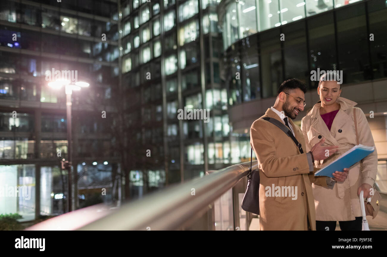 Geschäftsleute Schreibarbeit diskutieren auf städtischen Fußgängerzone Bridge bei Nacht Stockfoto