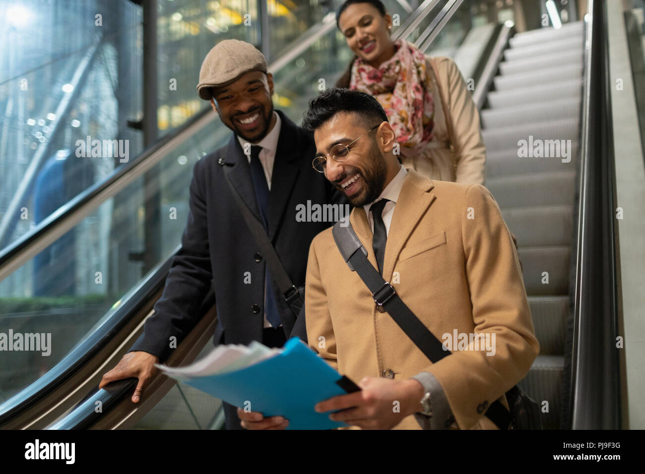 Lächelnd Geschäftsleute Papierkram lesen auf Rolltreppe Stockfoto