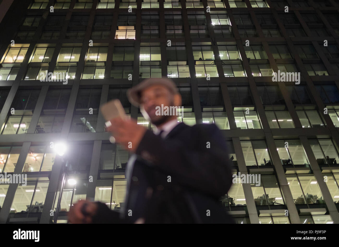 Geschäftsmann mit smart phone unter städtischen Hochhaus in der Nacht Stockfoto