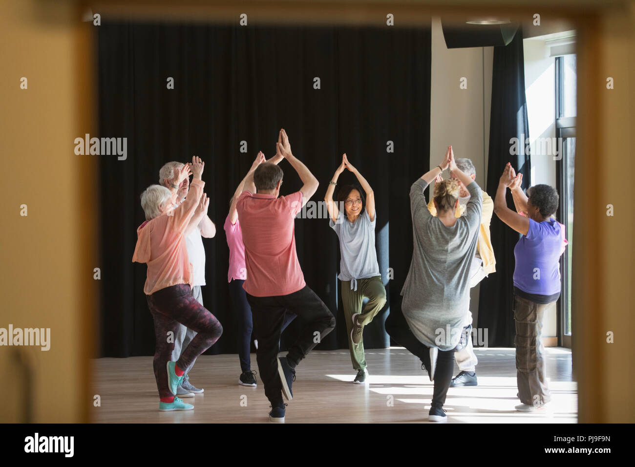 Aktive Senioren trainieren im Kreis, Üben Yoga die Baumhaltung Stockfoto