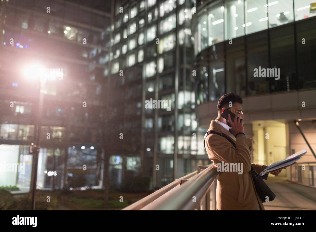 Unternehmer im Gespräch über Smart Phone, lesen Schreibarbeiten auf städtischen Fußgängerzone Bridge bei Nacht Stockfoto