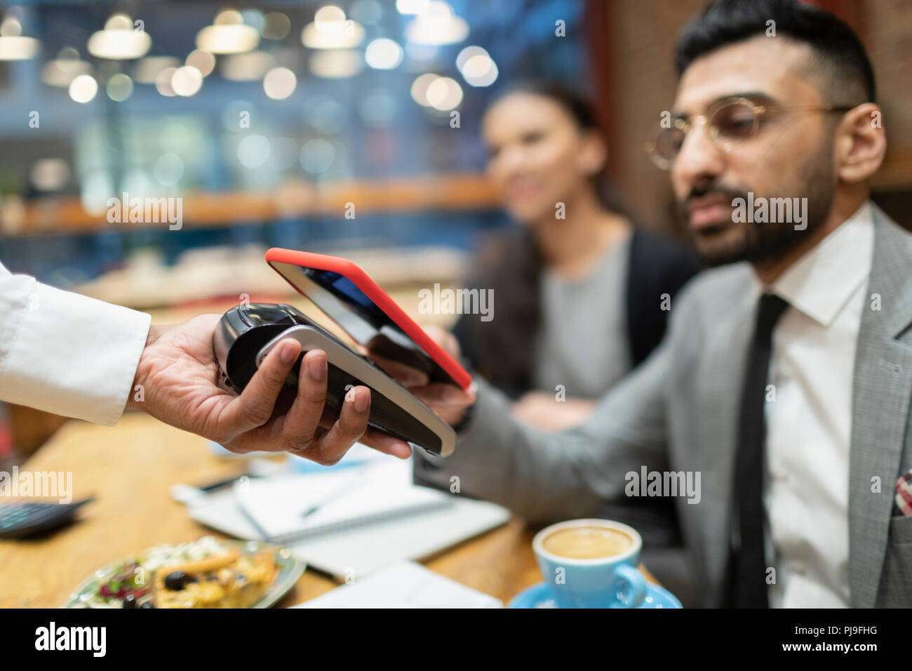 Unternehmer im Cafe bezahlen mit smart phone kontaktloses Bezahlen Stockfoto