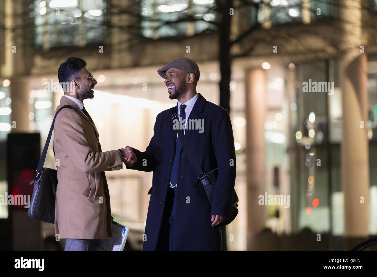 Unternehmer handshaking auf städtischen Straße bei Nacht Stockfoto