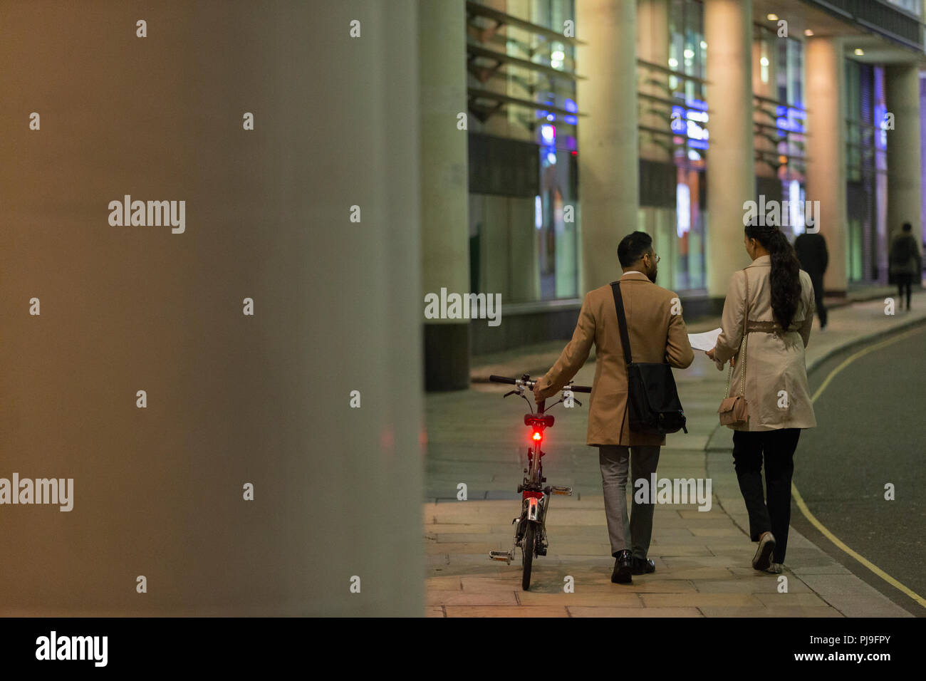 Geschäftsleute mit dem Fahrrad zu Fuß auf städtischen Gehsteig in der Nacht Stockfoto