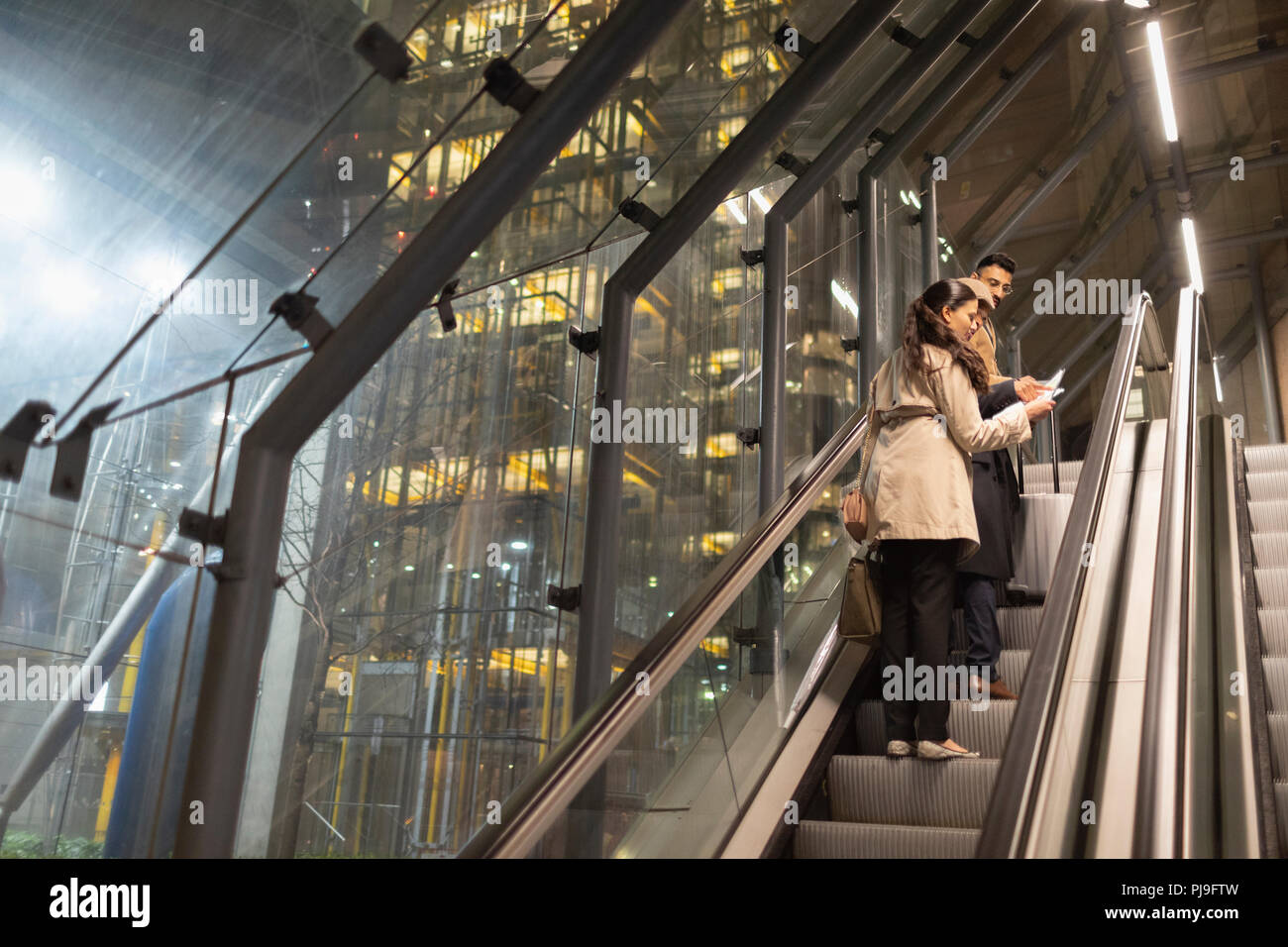Geschäftsleute mit Koffer sprechen auf städtischen Rolltreppe in der Nacht Stockfoto