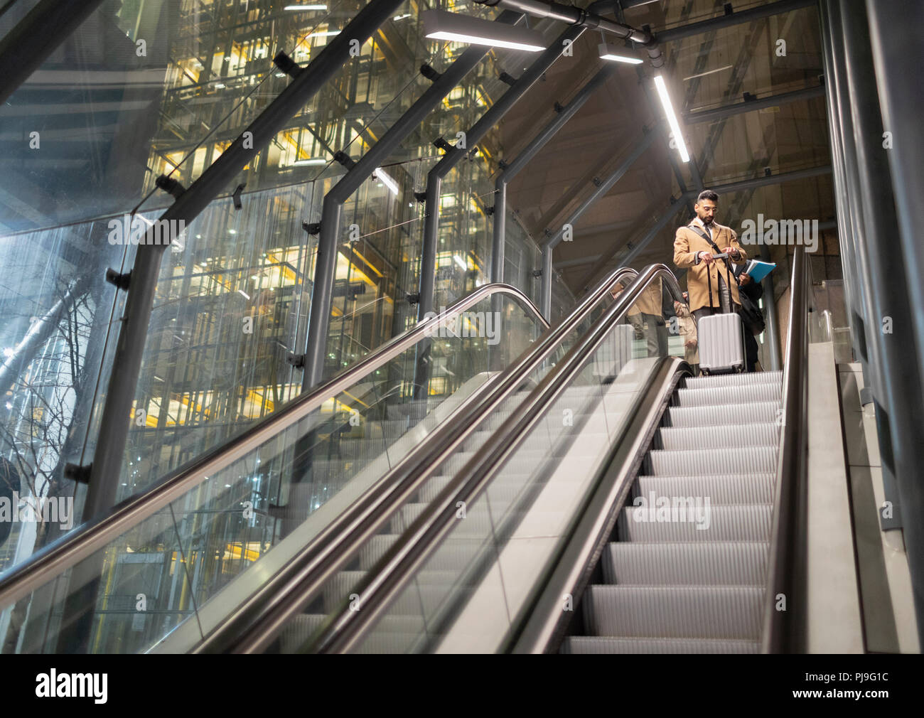 Geschäftsmann mit Koffer auf städtischen Rolltreppe Stockfoto