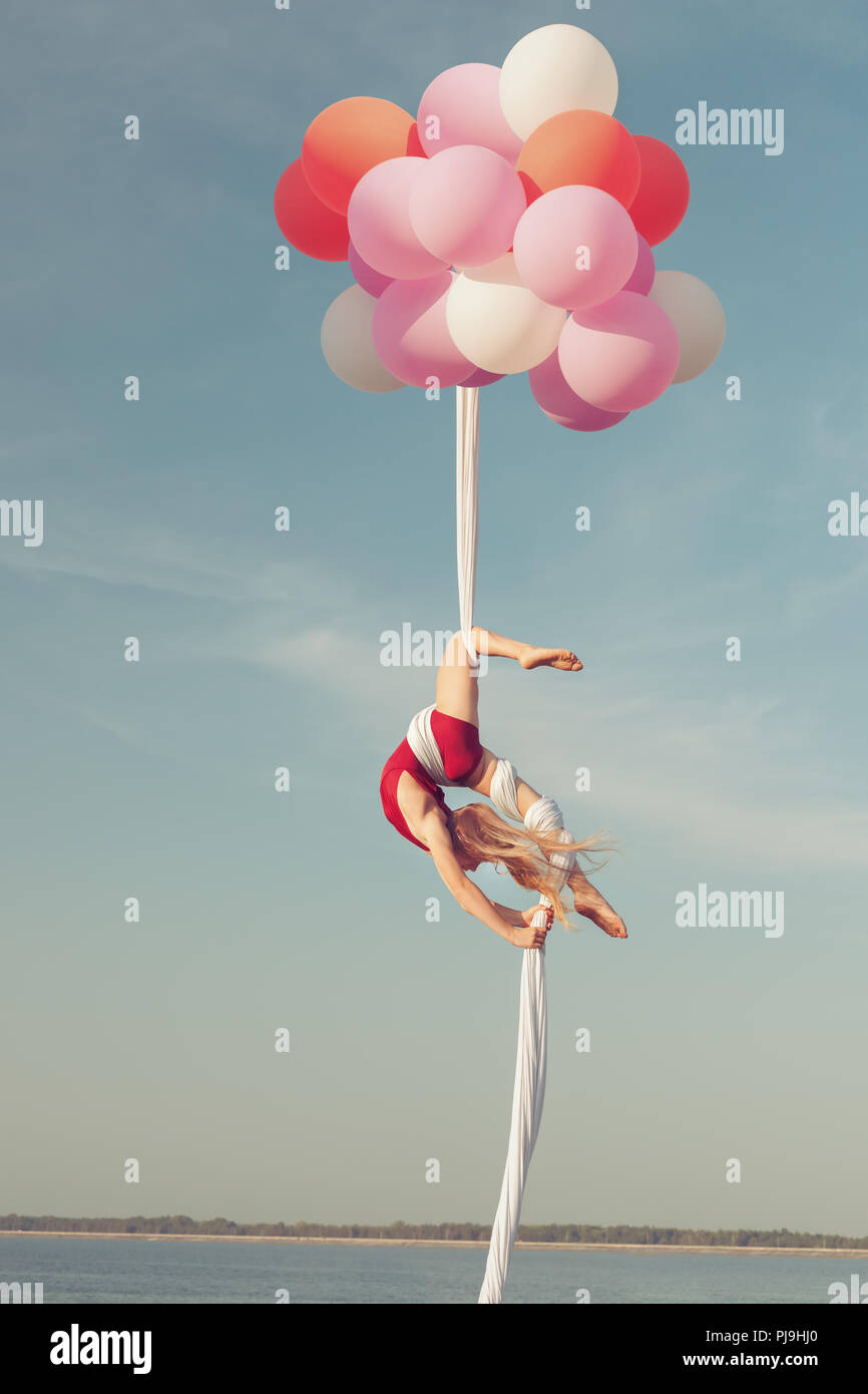 Girl hat akrobatischen Stunts. Sie schwebt in der Luft auf Luftballons. Stockfoto