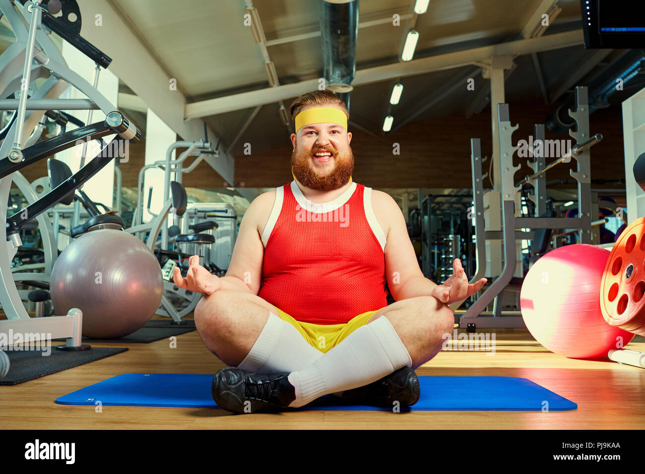 Lustige fetter Mann mit einem Bart Yoga in der Turnhalle Stockfoto
