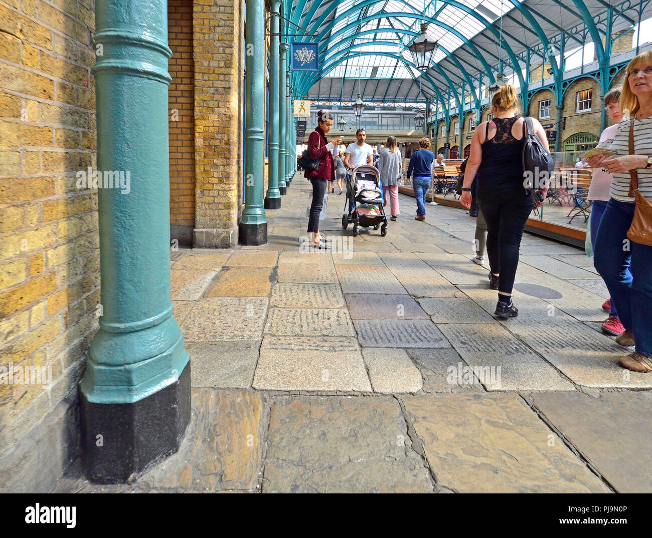 Frau ihre Telefon- und Mann treibt ein Panda, Covent Garden Covered Market, London, England, UK. Stockfoto