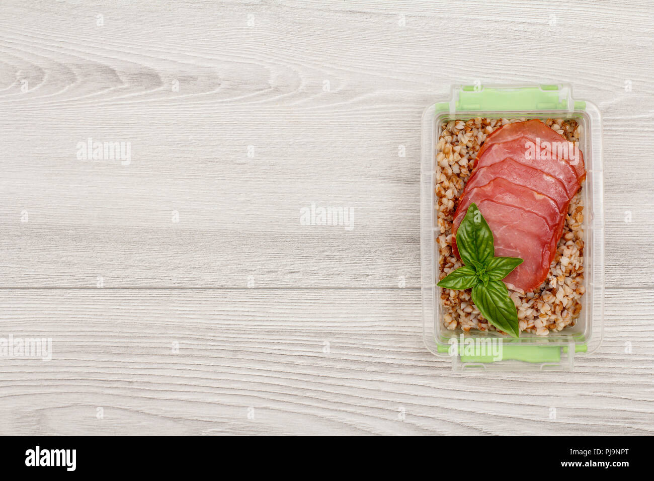 Kunststoff Mahlzeit prep Container mit gekochten Buchweizen Brei und Scheiben von Fleisch auf grau Holz- Hintergrund. Ansicht von oben mit der Kopie Raum Stockfoto
