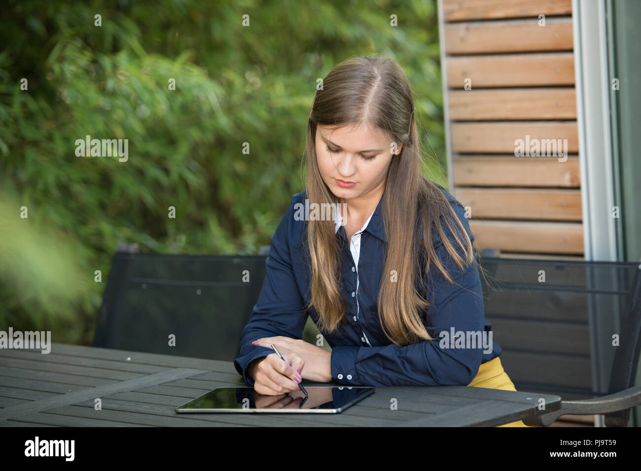 Junge Frau mit tablet pc, draußen zu sitzen, arbeitet mit Stylus Stockfoto