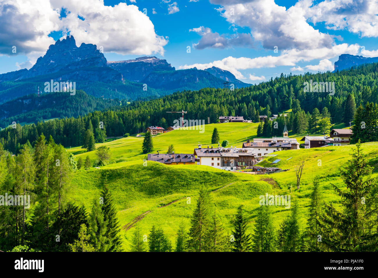Ausblick auf den kleinen Dorf und dem hohen Berg am Giau Pass in Italien mit dem Dorf und den Wald von Pinien Stockfoto