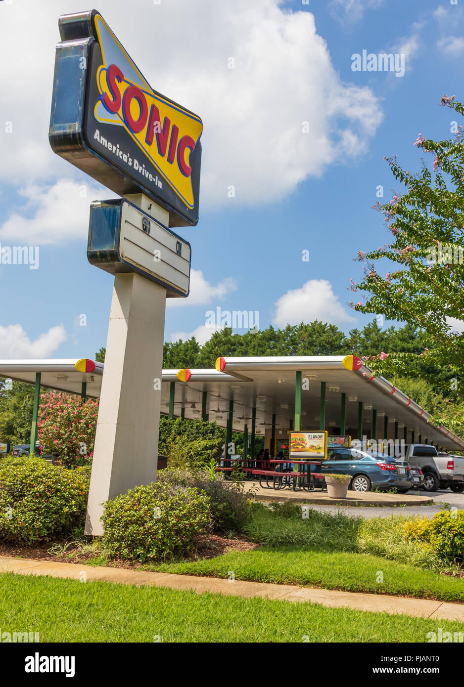 NEWTON, NC, USA -9/2/18: Ein Sonic Drive-in Fast Food Restaurant, zeigt ein Straßenschild und Service. 4 Personen am Tisch sichtbar unter der Markise. Stockfoto