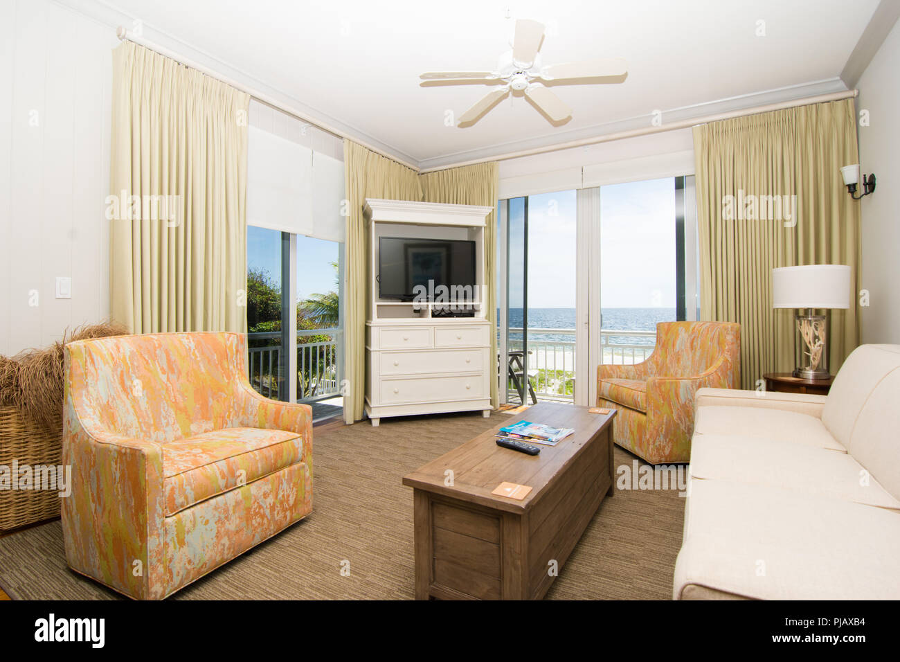Ein geschmackvoll eingerichtetes Wohnzimmer mit Terrassentür mit Blick auf den Ozean. Stockfoto