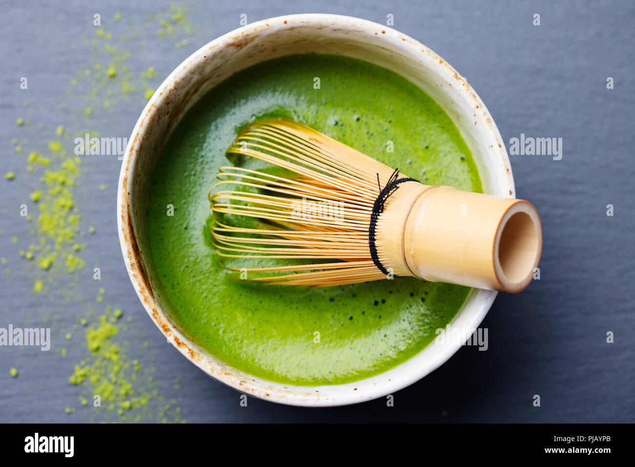 Matcha Grüntee Zubereitung in einer Schüssel mit bambusbesen. Schwarzer Schiefer Hintergrund. Ansicht von oben. Stockfoto