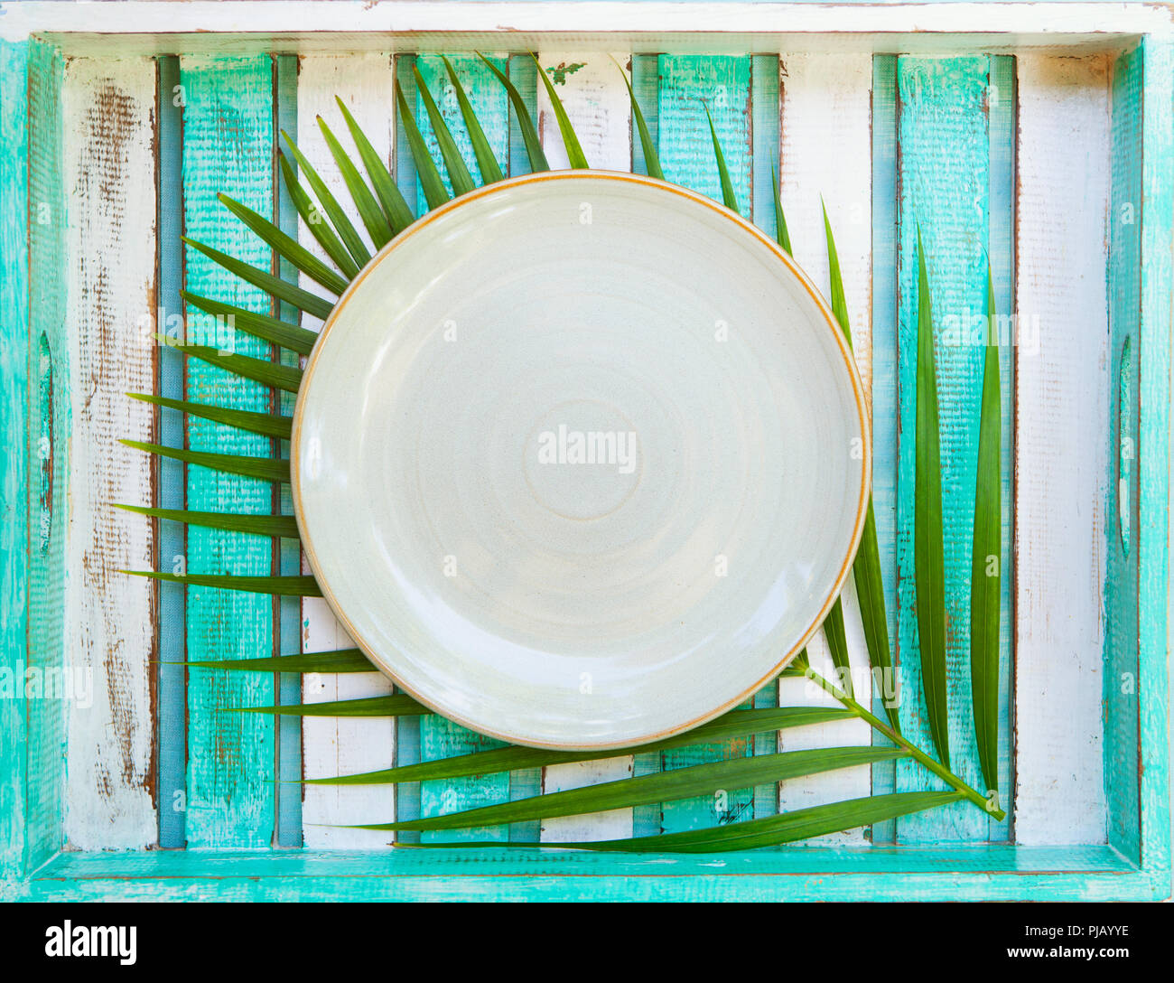 Weiße Platte mit palm leaf auf Holz- Hintergrund. Kopieren Sie Platz. Ansicht von oben. Stockfoto