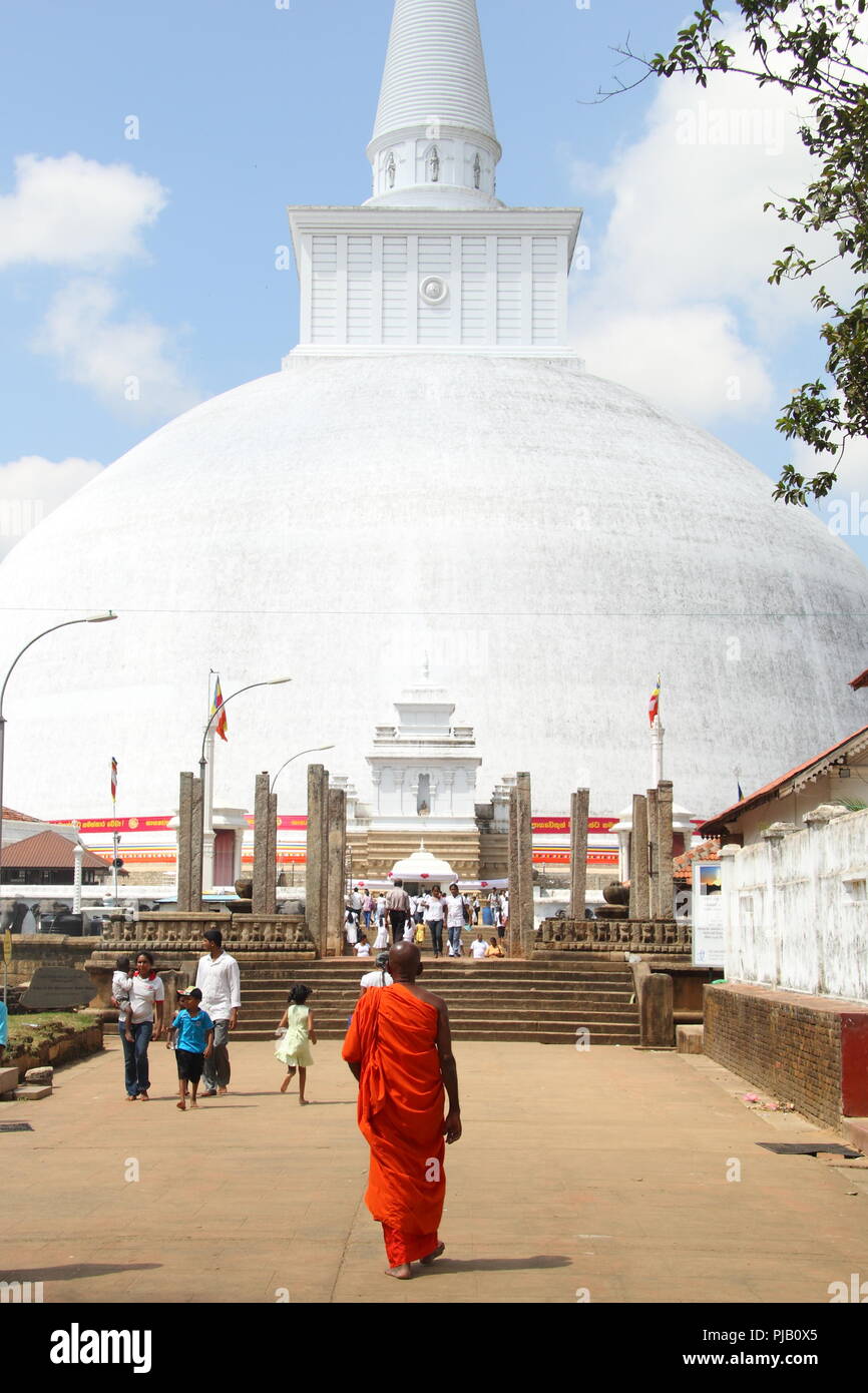 ANURADHAPURA, SRI LANKA - FEBRUAR 01: Buddhistischer Mönch in orangefarbenem Gewand geht am 1. Februar 2015 in Anuradhapu in Richtung des alten weißen Ruwanwelisaya Stupa Stockfoto