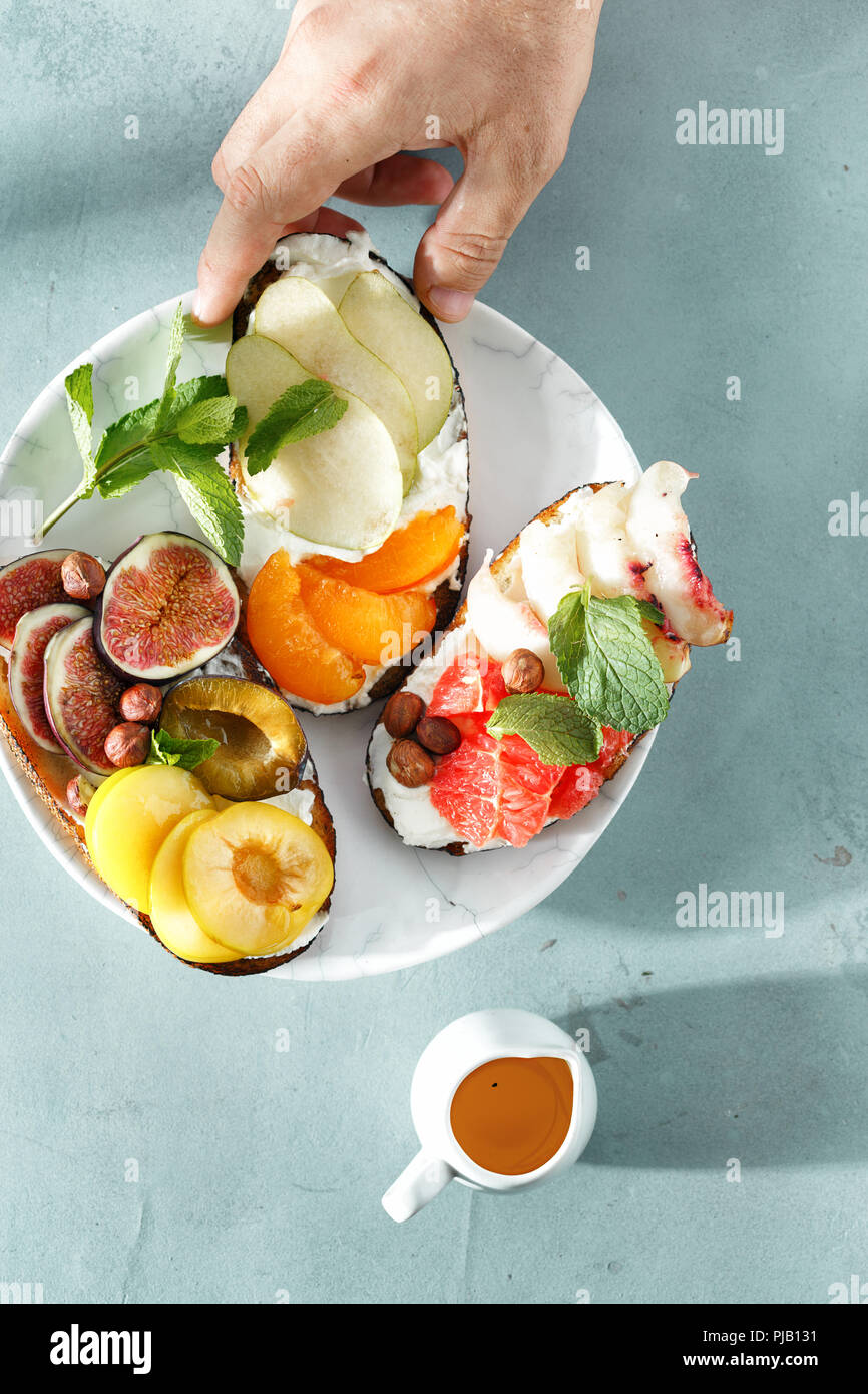 Gesundes und schmackhaftes Frühstück Konzept. Verschiedene Sandwiches mit Obst auf Stein Hintergrund, Ansicht von oben Stockfoto