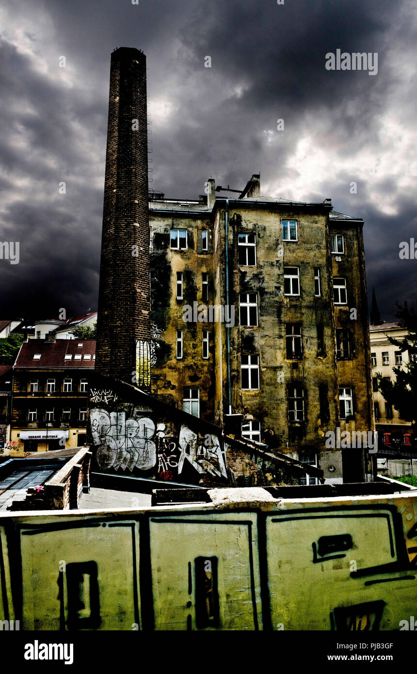 Dramatische Szene mit Gebäuden und industriellen Schornstein in Ruin und Dunkler Himmel Stockfoto