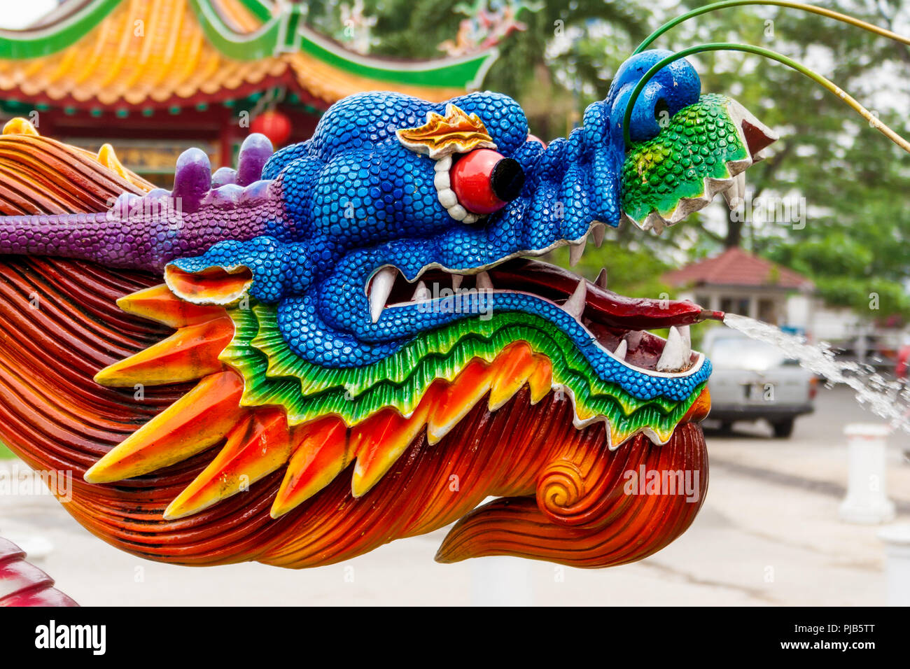 Eine schöne Nahaufnahme von einem bunten Wasser spritzen Dragon Head bei einem chinesischen Tempel. Der Wasserstrahl kommt aus seiner Zunge. Stockfoto