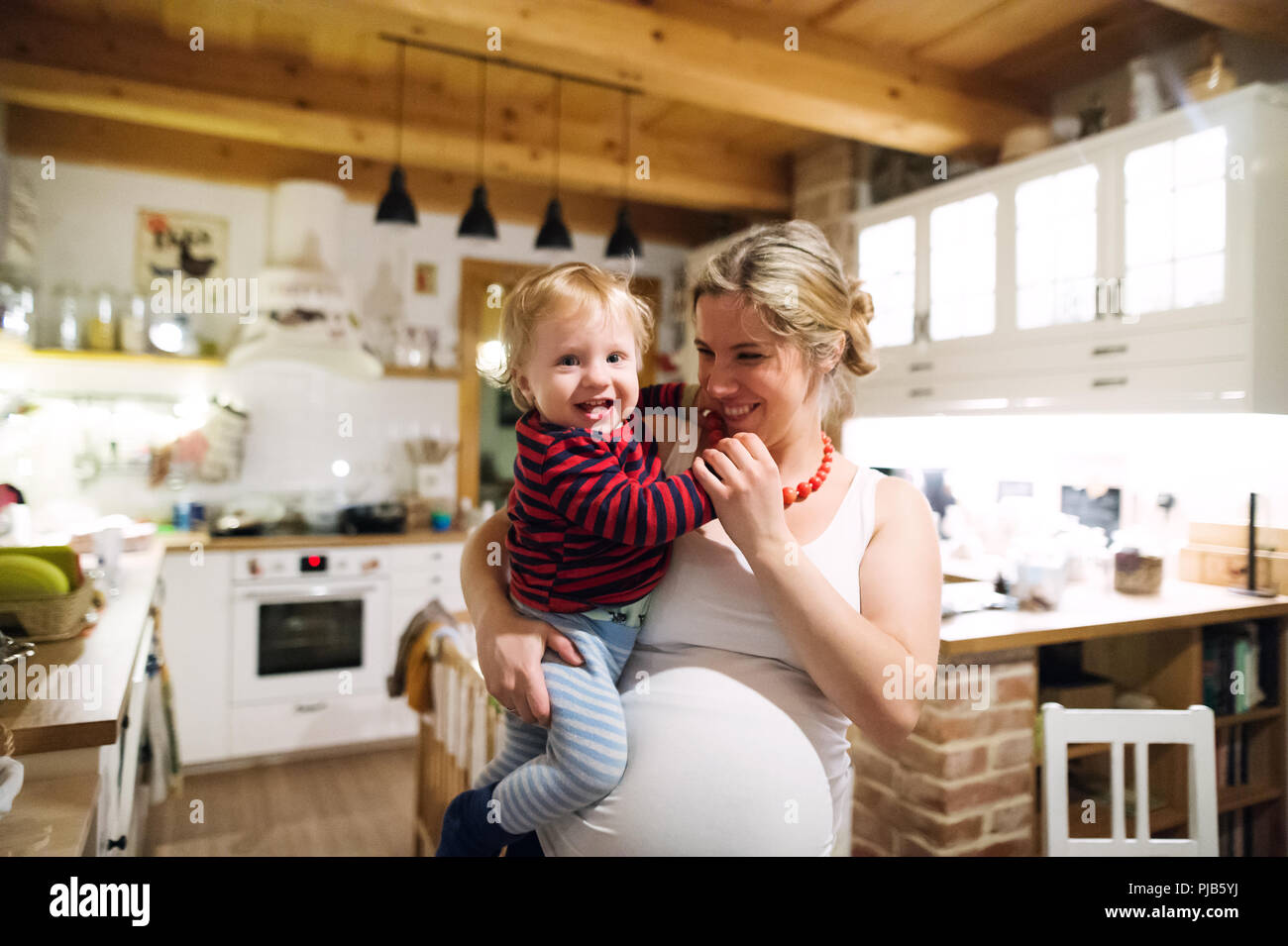Schöne schwangere Frau mit einem Kleinkind Junge in der Küche zu Hause. Stockfoto