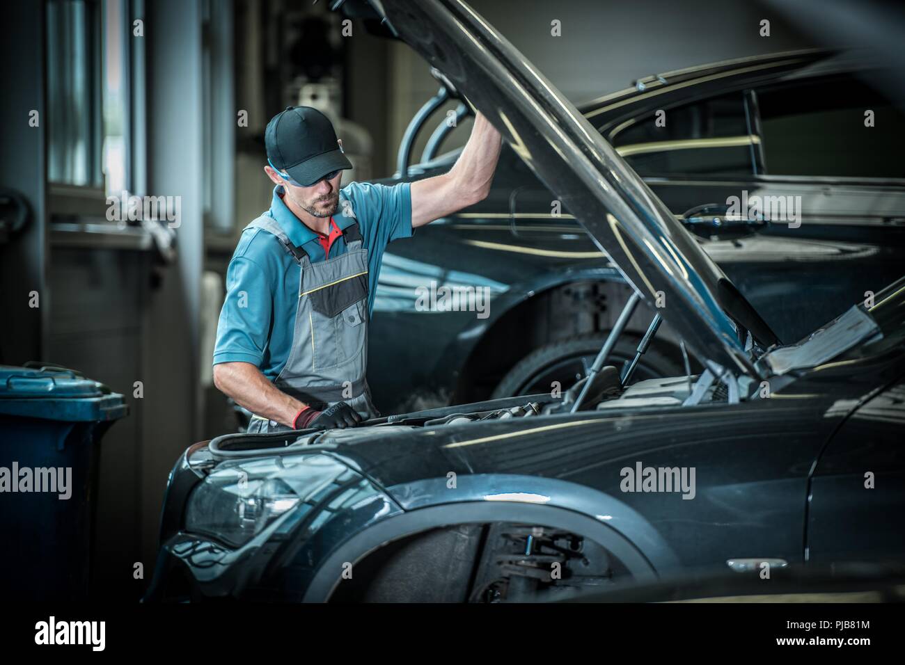 Automechaniker und seinen Job. Kaukasische Auto Service Arbeitnehmer vor defekten Fahrzeug. Stockfoto