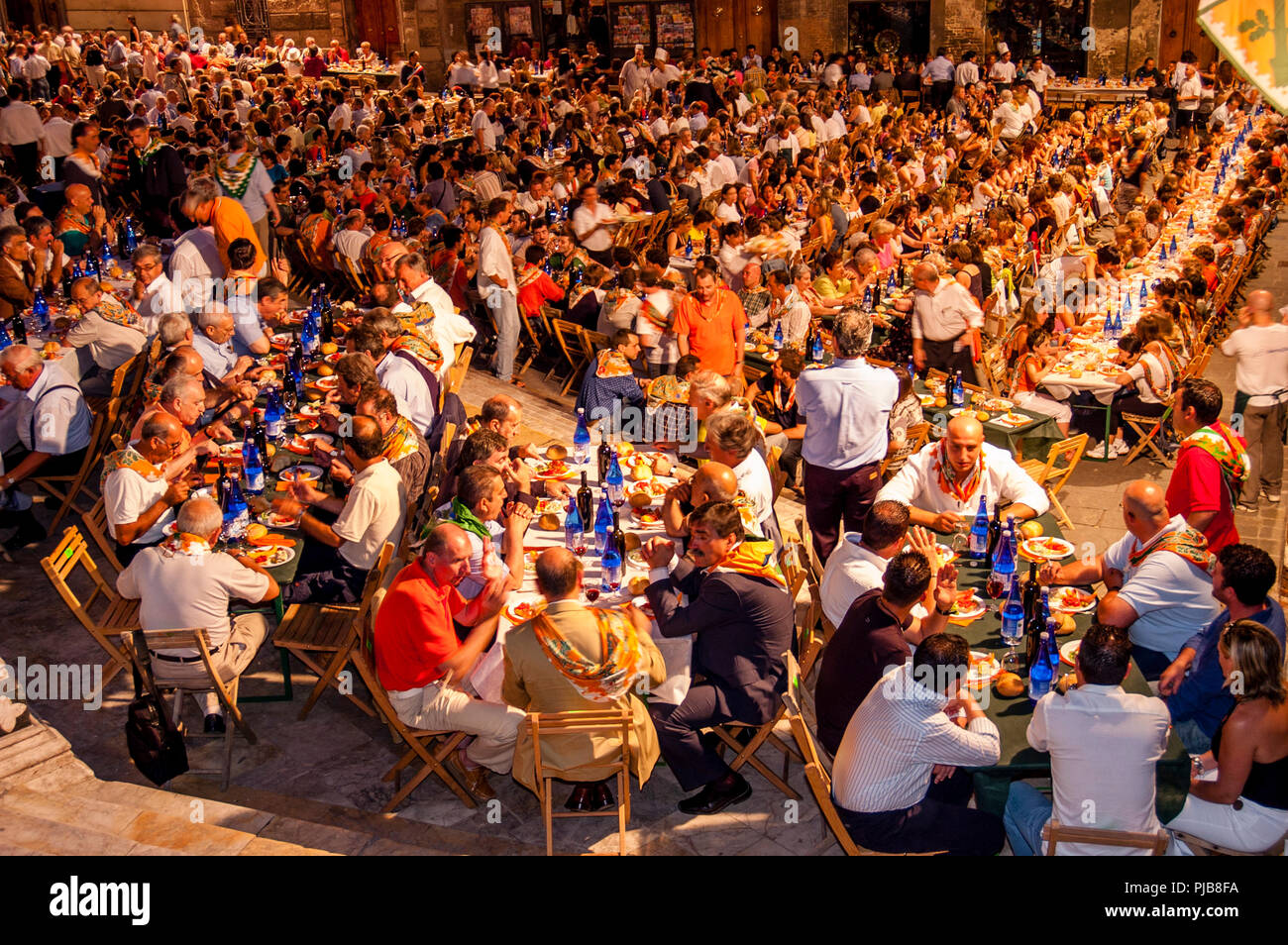 Die Mitglieder der Selva (Forest) Contrada nehmen am traditionellen „Eve of Palio“-Gemeinschaftsessen Teil, dem Palio di Siena, Siena, Italien Stockfoto