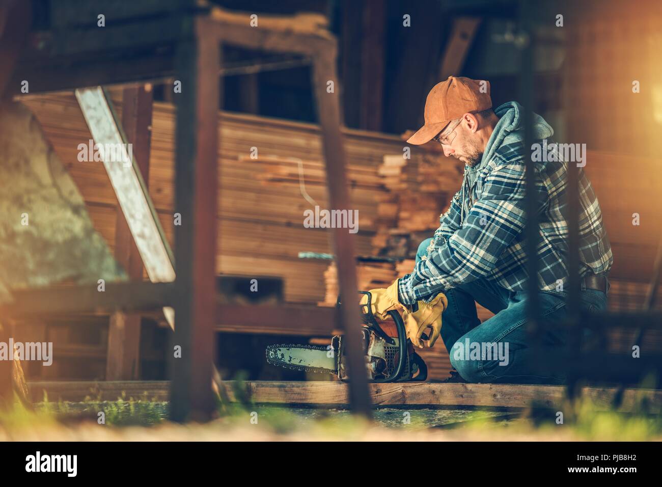 Kleine Hausarbeit Projekt. Kaukasischen Männern in seinem 30s mit Benzin Kettensäge Vorbereitung für einige Arbeiten im Inneren der Scheune. Stockfoto