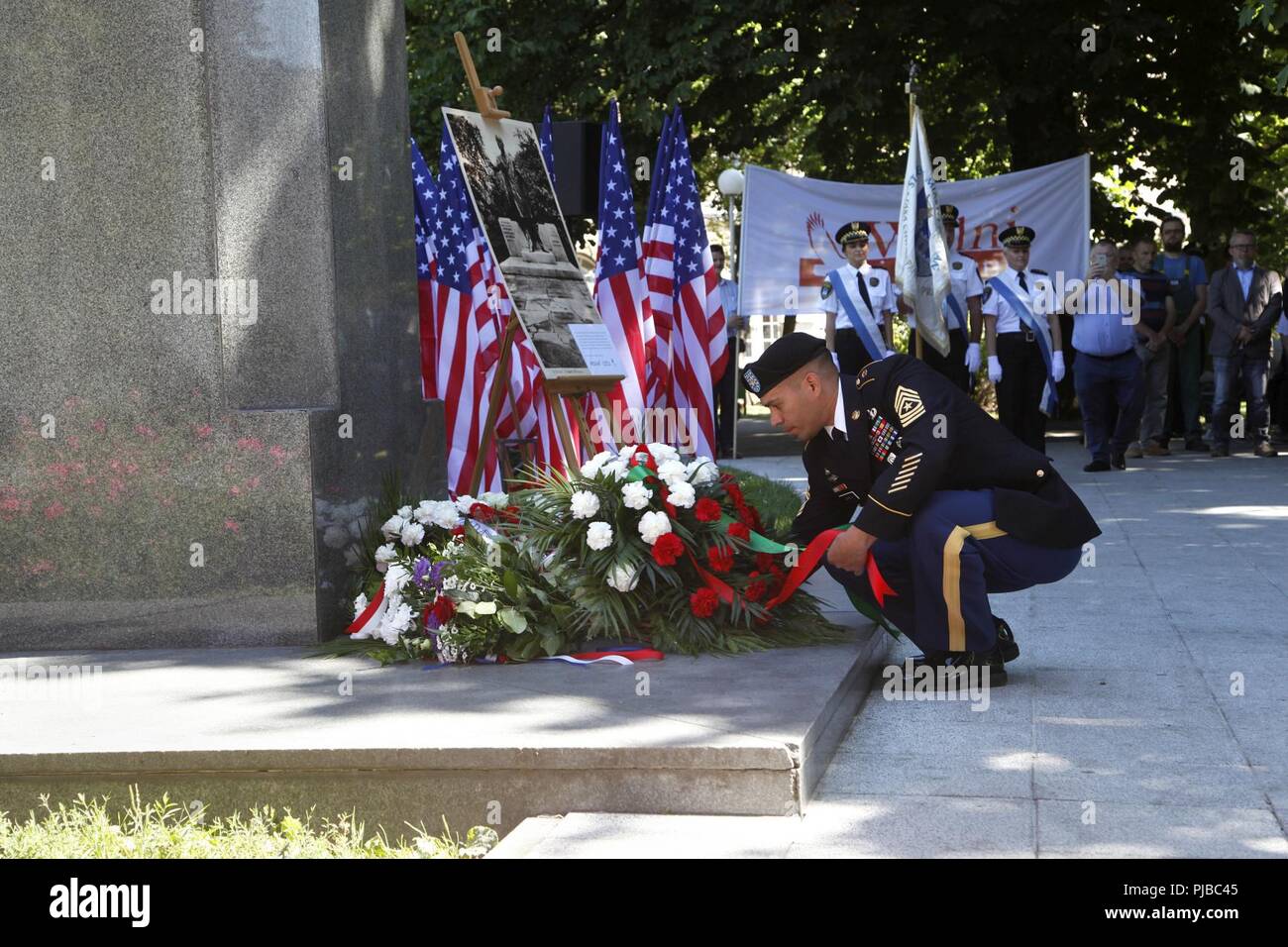 Sergeant Maj Sael Garcia, der 1.infanteriedivision Mission Befehl Element Sergeant Major, legt Blumen an der Präsident Woodrow Wilson Denkmal während einer Zeremonie im Wilson Park, Poznań, Polen, 4. Juli 2018, Wilson's Beiträge zur Unabhängigkeit Polens zu gedenken. Jan. 8, 1918, Wilson gab seine "Vierzehn Punkte" Rede, die auf einem friedlichen Weg aus der Zeit des Ersten Weltkriegs. Punkt 13 angegeben, "eines unabhängigen polnischen Staates errichtet werden sollte, das die Gebiete von unbestreitbar der polnischen Bevölkerung bewohnt, die ein freier und sicherer Zugang zum Meer gesichert werden sollten, gehören sollte, eine konzentrierte Stockfoto