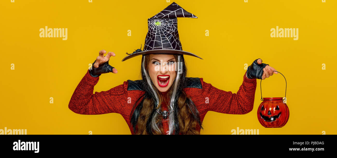 Bunte Halloween. moderne Frau in Halloween Hexe Kostüm auf gelben Hintergrund mit Jack-o-Lantern erschreckend Stockfoto