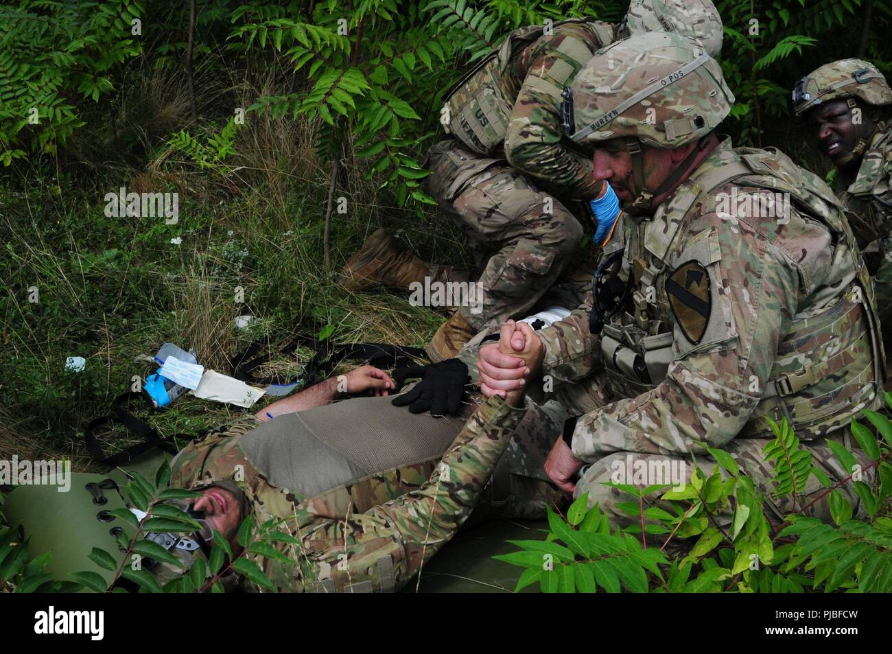 Army Staff Sgt. Jordan Murzyn an den Spähtrupp, Sitz und die Konzernzentrale, 2nd Battalion, 5th Cavalry Regiment, 1st Armored Brigade Combat Team, 1.Kavallerie Division Konsolen Armee Pvt. 1. Klasse Eric Martinez zu den Spähtrupp, HHC, 2-5 Cav, 1 ABCT, 1 CD aufgrund einer simulierten Verletzungen am Mihail Kogalniceanu Airbase in Rumänien, 10. Juli 2018 zugewiesen. Soldaten führte eine Air Assault Training zur Unterstützung der Atlantischen lösen, ein bleibendes Training übung zwischen der NATO und der US-Streitkräfte. Stockfoto