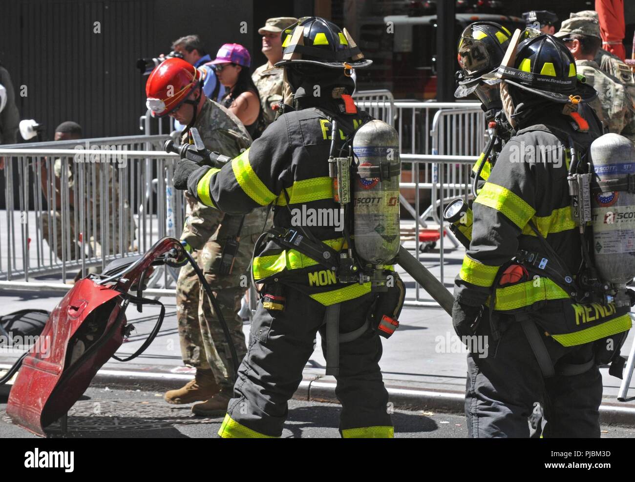 Ein U.S. Army Reserve Staff Sgt. Eric Huggins mit der 468Th Engineer Detachment (Brandbekämpfung Hauptsitz), 368 Techniker Bataillon, 302d Manöver Verbesserung Brigade, 412 Theater Ingenieur Befehl in Danvers, Massachusetts zieht die Tür von einem Fahrzeug während einer aus verunfallten Fahrzeugen als Feuerwehr der Stadt New York (FDNY) halten einen Wasserschlauch bereit, während einer aus verunfallten Fahrzeugen n der New York City chemischen, biologischen, radiologischen und nuklearen (CBRN) Gemeinsame Ausbildung Übung (JTE) am Times Square Church in New York City, New York, 10. Juli 2018. Das fdny mit US-Armee Nort Stockfoto