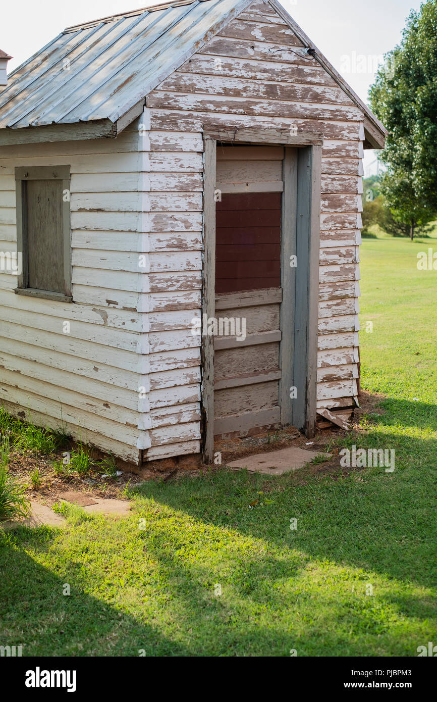 Ein altes verwittertes Holz- Werkzeug mit abblätternder Farbe und ein Blechdach auf einem ländlichen Bauernhof in Oklahoma, USA. Stockfoto