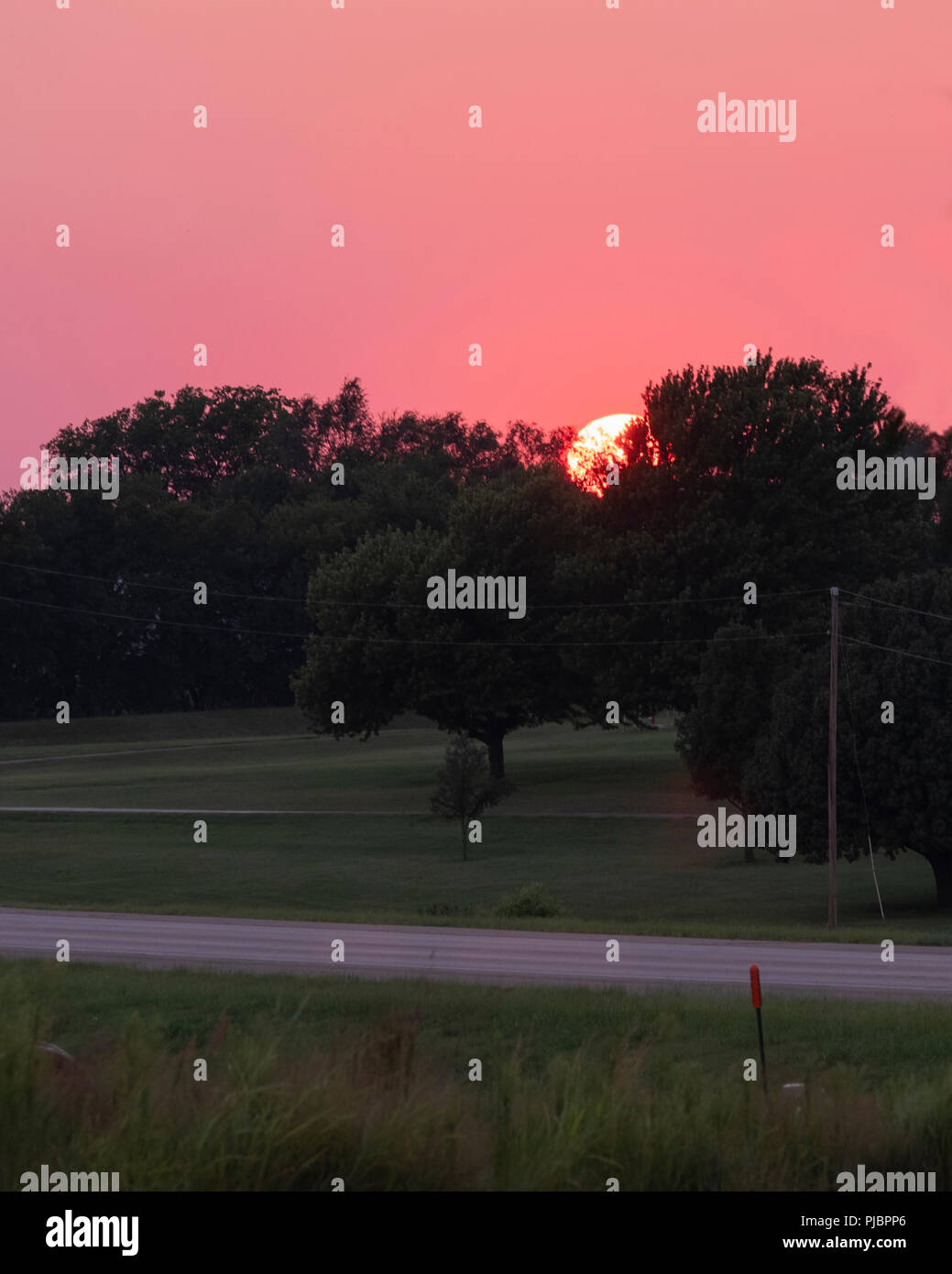 Orange Ball der untergehenden Sonne in der Oklahoma, USA Landschaft. Glühende, rosa und lila Himmel. Stockfoto