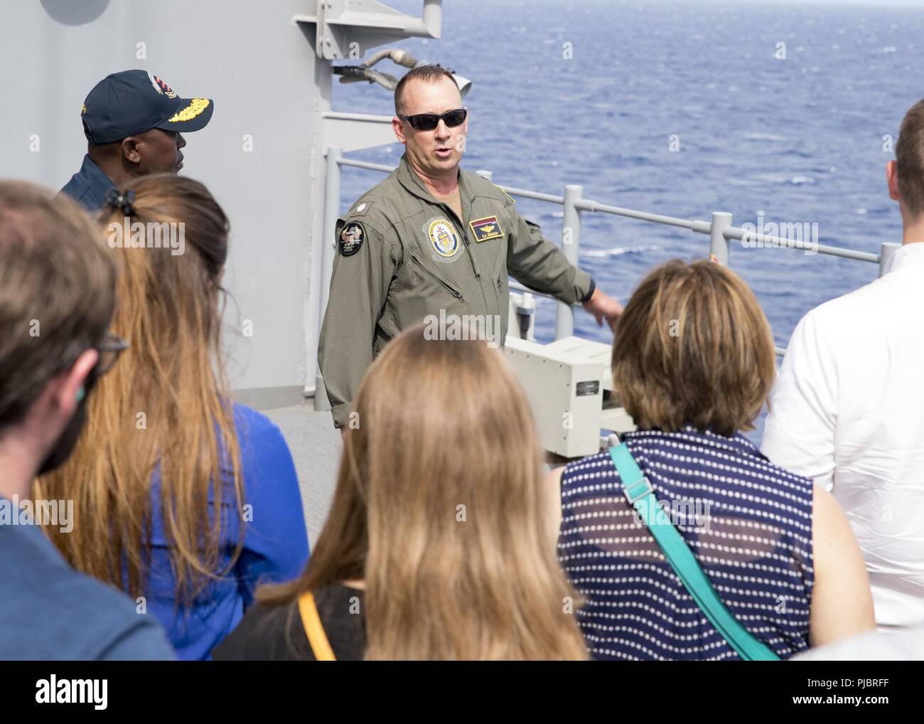 Pazifik (13 Juli 2018) Cmdr. Scott Swagler, Abteilungsleiter, bespricht den Flugbetrieb mit Senatorial Personal Delegierten auf der Geier Reihe während einer Tour durch die Amphibious Assault ship USS BONHOMME RICHARD (LHD6) während der Rand der Pazifischen (Rimpac) 2018 Übung. 25 Nationen, 46 Schiffe, 5 U-Boote, über 200 Flugzeuge und 25.000 Angestellte beteiligen sich an Rimpac vom 27. Juni bis 2. August in und um die hawaiischen Inseln und Südkalifornien. Die weltweit größte internationale maritime Übung RIMPAC bietet eine einzigartige Ausbildung während der Förderung und sustaini Stockfoto