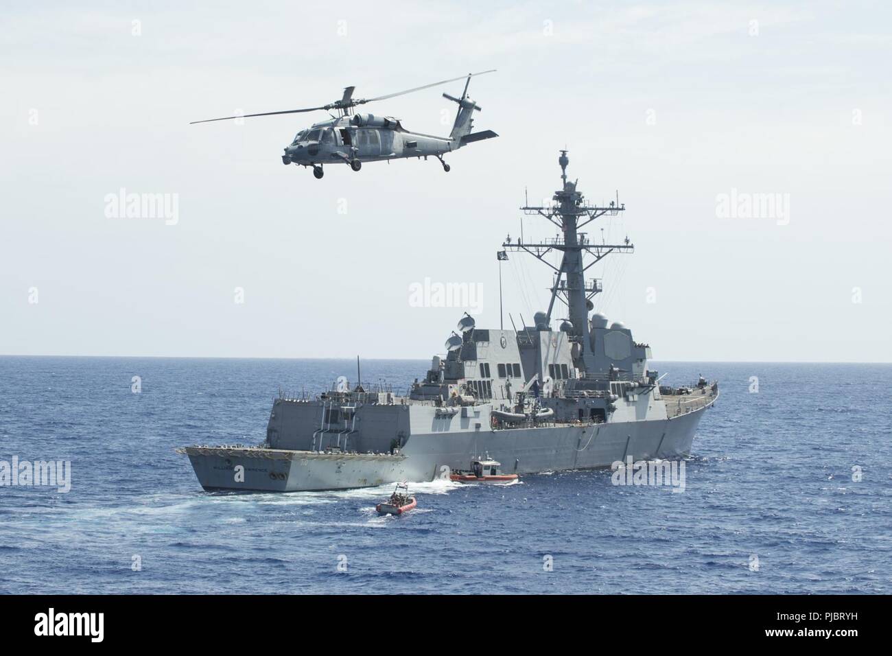 Pazifik (13. Juli 2018) eine US-Navy MH-60S Sea Hawk Hubschrauber, der "Schwarze Ritter" der Hubschrauber Meer Combat Squadron 4 zugeordnet, fliegen Overhead während die Küstenwache Maritime Security Response Team-West (MSRT) und kleinen Boot Besatzungen aus der U.S. Coast Guard Cutter WMSL Bertholf (750) Durchführung einer mock Boarding auf geführte Anti-raketen-Zerstörer USS William S. Lawrence (DDG110), 13. Juli, während der Rand des Pazifik (Rimpac) Übung. 25 Nationen, mehr als 46 Schiffe und 5 U-Boote, über 200 Flugzeuge und 25.000 Angestellte beteiligen sich an Rimpac vom 27. Juni bis 2. August in und aroun Stockfoto