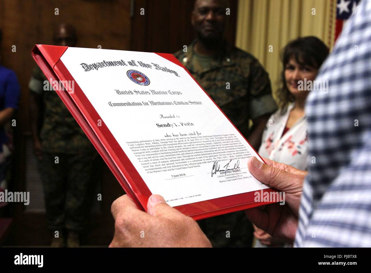 MCLB Albany Executive Director Kent Morrison liest das Zitat für die verdienstvollen Zivildienst Award, die Manpower Direktor Sendy Potts vorgestellt. Kommandierender Offizier Oberst Alphonso Trimble Mrs Potts für ihre herausragende Leistung der Pflicht anerkannt, während die Leitung für das Marine Corps Installationen Partnerschaft Programm dienen. Stockfoto