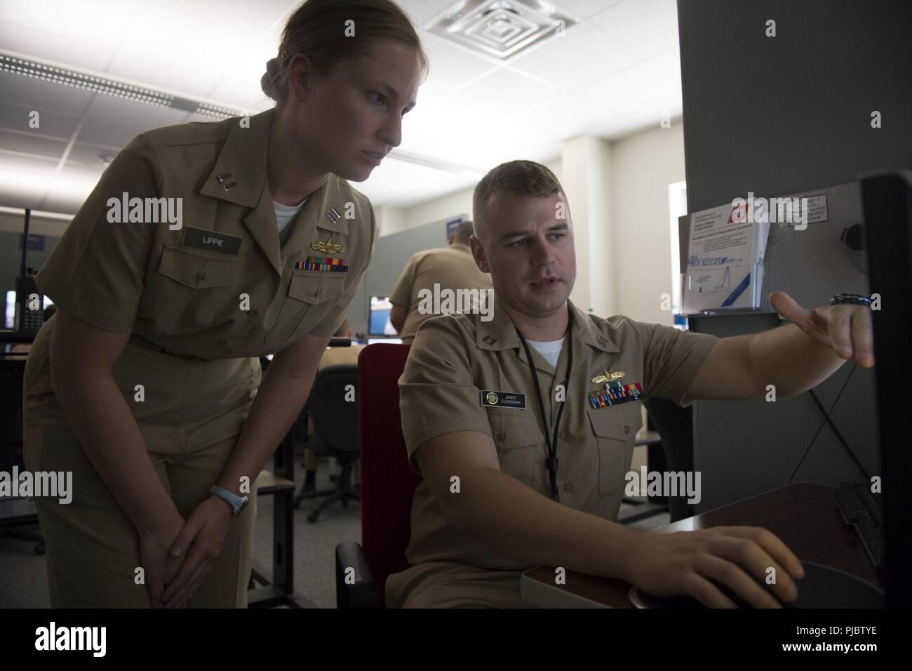 NEWPORT, R.I. (11. Juli, 2018) Leutnant Elizabeth Lippie von Fort Wayne, Indiana, eine erweiterte Division Officer Course (adoc) Student zugeordnet Oberfläche Kriegsführung Offiziersschule (SWOS), erhält ein Feedback vom Ausbilder Leutnant Jim Clendenin von Auburn, Virginia, auf shiphandling Techniken und Pier mit dem conning Officer virtuelle Umgebung (COVE) Simulator. Die COVE Simulator bietet State-of-the-art Navigation und shiphandling Ausbildung und können sich die US-Marine homeports und fast jede Routine Anlaufstelle rund um die Welt emulieren. In Newport, Rhode Island mit Sitz und Überwachung neun Lear Stockfoto