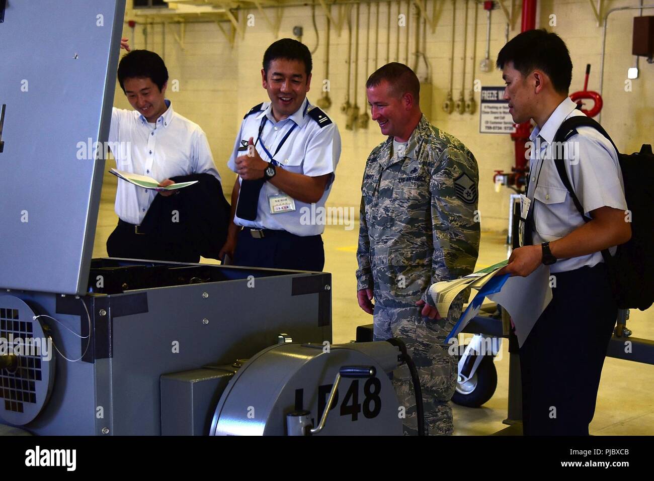 Master Sgt. Nicholas Shurtz, Wartung 931st Squadron Air Ground Equipment Section Chief, lacht mit Japan Air Verteidigung-kraft Vertreter während der Anzeige Vergleiche der KC-46 Pegasus und KC-135 Stratotanker aerospace Ground Equipment Juli 11, 2018, McConnell Air Force Base, Kansas. Demonstrationen wurden sowohl für die Wartung und Sicherheit der Ausrüstung, die die JASDF für die KC-46 Ankunft vorbereiten. Stockfoto