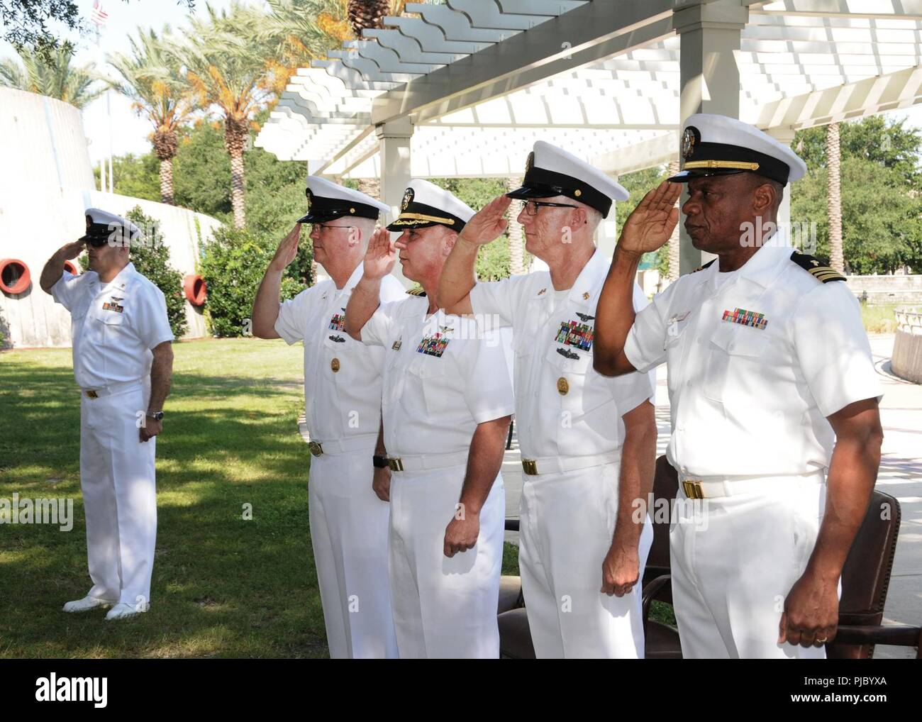 JACKSONVILLE, Fla. (Juli 13, 2018) von links nach rechts, Chief Petty Officer Steven Cordero, Command Master Chief Jeremy Brücken, Kapitän Trent DeMoss, Command Master Chief Donald Henderson und Kaplan James Askiew salute wie der Color Guard vorbei von Henderson's Ruhestand Festakt in Jacksonville die Freundschaft Brunnen. Stockfoto