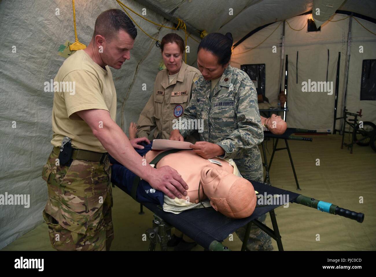 Tech. Sgt. Frank Yuvan, Links, eine eigenständige Pflicht medizinischer Techniker (IDMT) von der 421St Combat Training Squadron, Laura Prestidge, eine Krankenschwester mit dem WI-1 Disaster medizinische Hilfe Team (DMAT) und Maj. Melodie Yung, ein Arzt, der Assistant von der 108 Medical Group, eines Patienten während der PATRIOT Nord 18 bei Volk Feld, Wis., 18. Juli 2018. PATRIOT ist ein inländischer Betrieb Disaster Response Training durch die National Guard Einheiten arbeiten mit Bundes-, Landes- und lokale Emergency Management Agenturen und Ersthelfer durchgeführt. Stockfoto