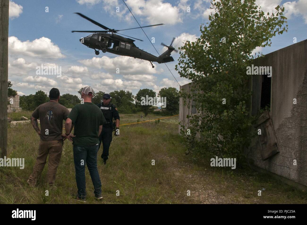 Ein Mitglied der Wisconsin State Patrol simuliert, um die Besatzung des Wisconsin Army National Guard UH-60 Blackhawk Helikopter liefern das Wasser für notleidende Bürger in einem Szenario während der PATRIOT Nord 18 am Fort McCoy, Wis., 18. Juli 2018. PATRIOT ist ein jährlicher Inland Training durch die Nationalgarde gefördert, die auf die Erhöhung der Fähigkeit der lokalen, staatlichen und föderalen Organisationen zu koordinieren zusammen arbeiten als Reaktion auf Naturkatastrophen oder von Menschen verursachten Not- und konzentriert. Stockfoto