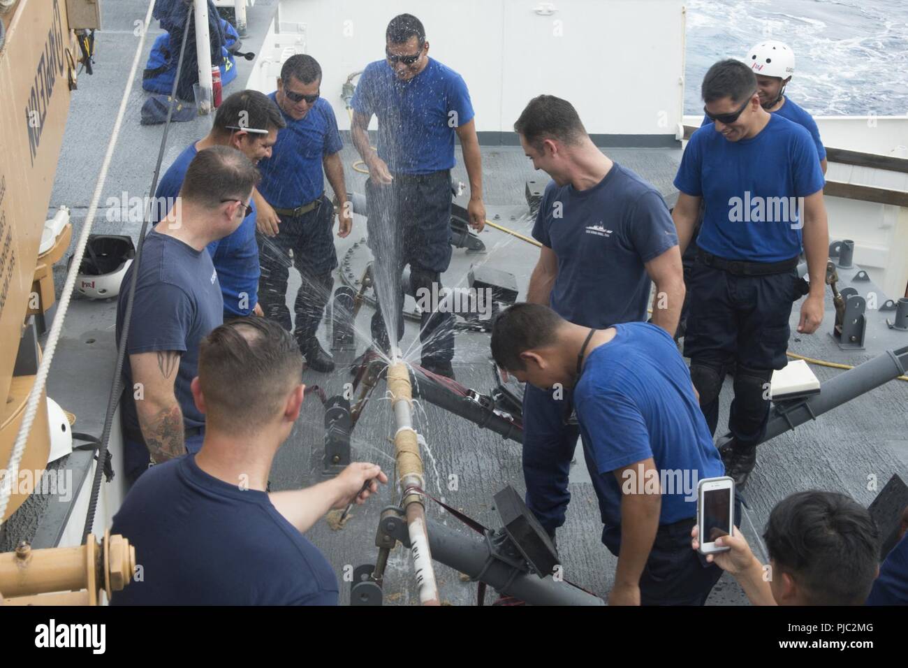 Pazifik (19 Juli 2018) Besatzungsmitglieder der U.S. Coast Guard Cutter WMSL Bertholf (750) und die Peruanische Marine maritime Patrol Boot BAP Ferré (PM211) werden durch Wasser während einer Beschädigung Kontrolle ausübt, ein undichtes Rohr während der Pacific Rim (Übung RIMPAC) 2018, 19. Juli zu reparieren gesprüht. 25 Nationen, 46 Schiffe und fünf U-Boote, über 200 Flugzeuge und 25.000 Angestellte beteiligen sich an Rimpac vom 27. Juni bis 2. August in und um die Hawaiianische Insel und Südkalifornien. Die weltweit größte internationale maritime Übung RIMPAC bietet eine einzigartige Ausbildung während fosteri Stockfoto