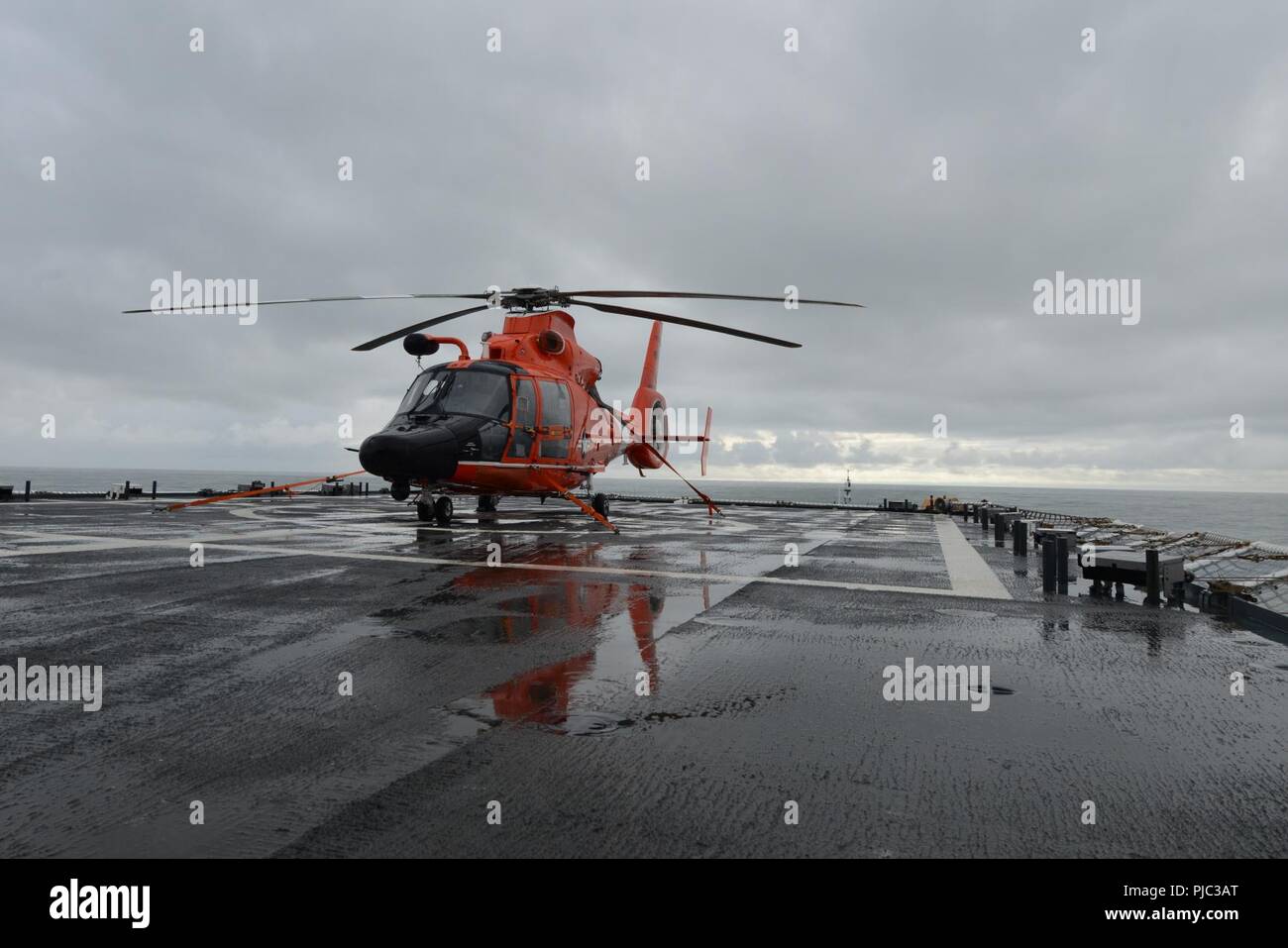 Einem MH-65 Dolphin Hubschrauber, schiffte sich an Bord der Coast Guard Cutter Stratton (WMSL 752), auf dem Flugdeck in Vorbereitung für einen Flug in der Nähe der Beringstraße, Juli 10, 2018 sitzt. Die stratton Crew patrouillieren oberhalb des Polarkreises zur Unterstützung der Operation Arktis Shield 2018. Küstenwache Stockfoto