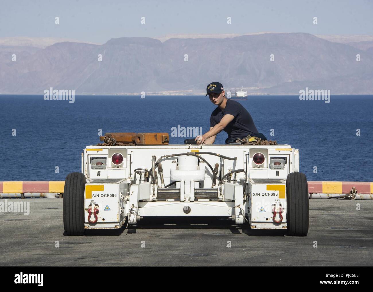 AQABA, Jordanien (9. Juli 2018) Aviation Support Equipment Techniker 2. Klasse Raymond Perez treibt die A/S32A-32 spotting Dolly auf dem Flugdeck an Bord der Wasp-Klasse amphibisches Schiff USS Iwo Jima (LHD7). Iwo Jima ist in die USA 5 Flotte Bereich der Maßnahmen zur Unterstützung der Marine im Einsatz für die Stabilität und Sicherheit in der Region zu gewährleisten und verbindet das Mittelmeer und den Pazifischen Raum durch den westlichen Indischen Ozean und drei strategischen Punkten ersticken. Stockfoto